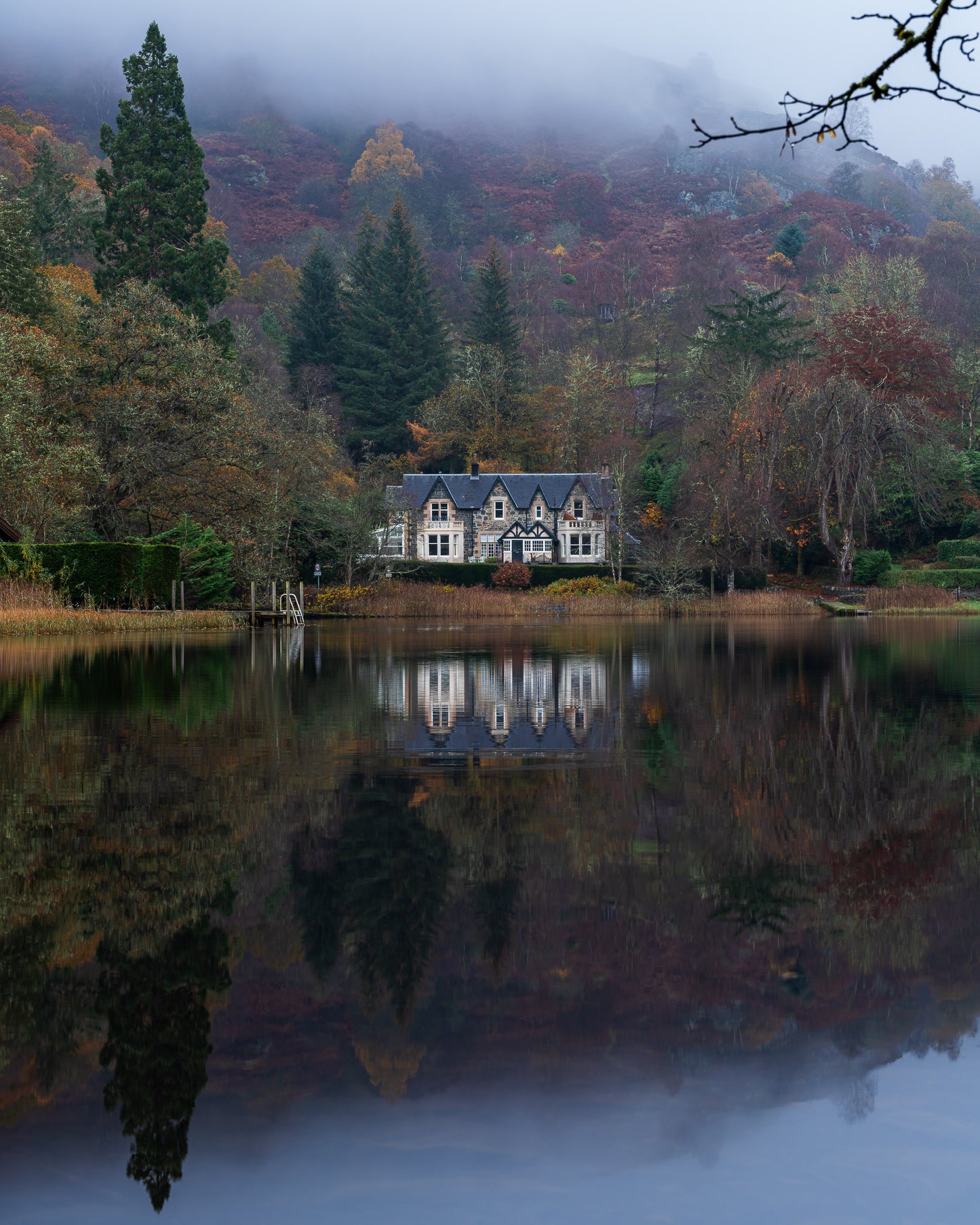 Reflet d'une maison sur le loch écossais en automne